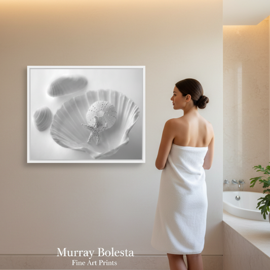 A woman wrapped in a white towel stands in a bright bathroom or spa-like interior, facing a framed black-and-white floral art print on the wall. The print appears to be the product being showcased, with the text 'Murray Bolesta Fine Art Prints' visible at the bottom.