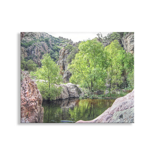 a serene arizona canyon natural landscape with a calm lake surrounded by lush greenery and rocky cliffs.