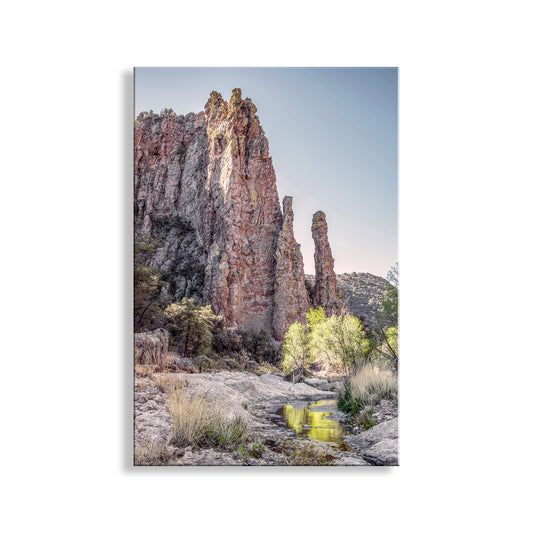 a serene natural landscape with towering red rock formations, a small stream, and lush vegetation.