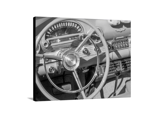 A close-up black and white photograph of the steering wheel and dashboard of a classic car, showcasing the intricate details and design elements of the vehicle's interior. Ford Thunderbird Wall Art – Black & White Classic Car Decor