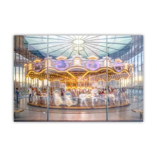 A brightly lit carousel with colorful lights and people enjoying the ride, captured through a glass window. Jane's Carousel Brooklyn NYC Art Print - East River Skyline Photo