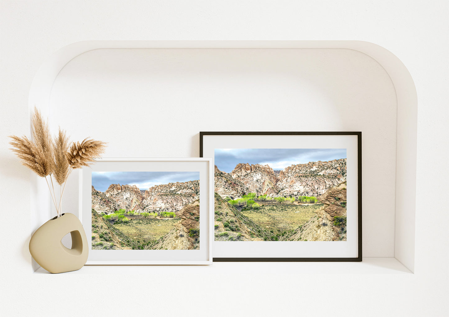 Two framed landscape prints on a white wall with decorative elements.