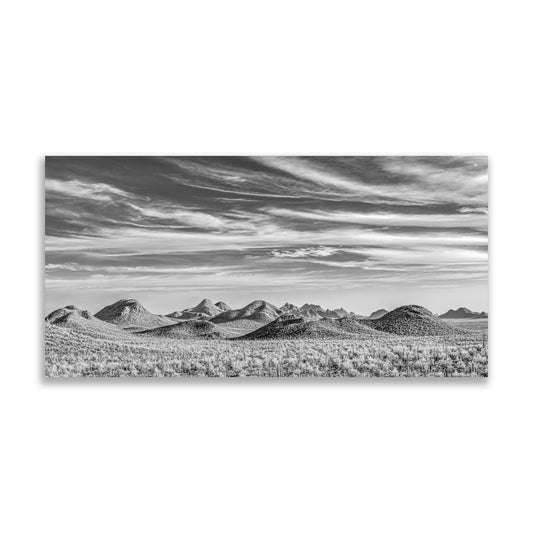 A black and white landscape photograph depicting a vast, open field with rolling hills in the distance under a cloudy sky. Tucson Desert Landscape Panorama Art | Black & White Photo Gift