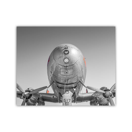 A large silver airplane with a propeller on each wing, facing forward.
