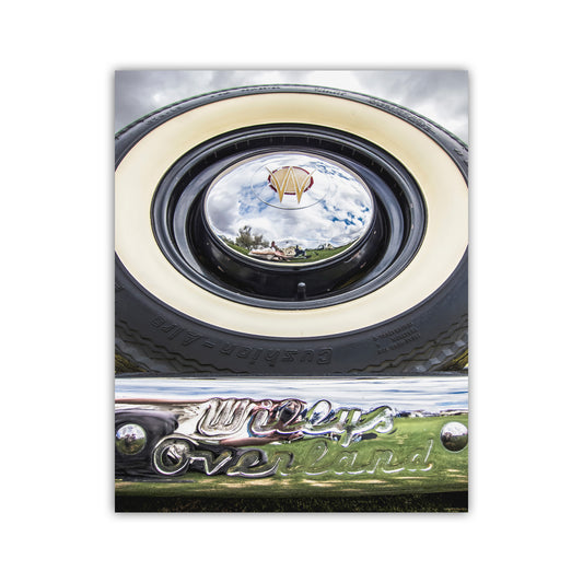 a close-up view of a vintage car's chrome bumper and round headlight, with a reflection of a kite in the center. Willys Overland Jeepster Classic Car Photography Art Print