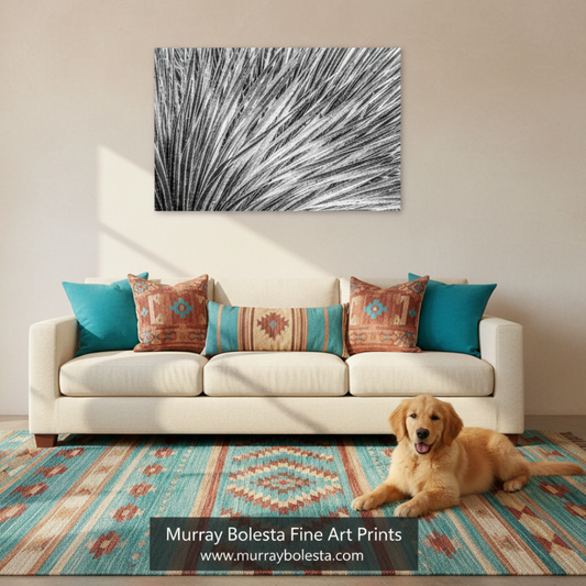 A framed abstract black, white, and gray brushstroke wall art print hangs above a white sofa in a styled living room. A golden retriever lies on a turquoise and cream patterned rug in front of the sofa.