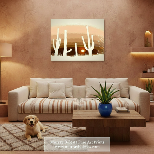 A framed wall art print showing white cacti against a warm sunset landscape, displayed above a beige sofa in a styled living room with a dog on a rug and a coffee table.