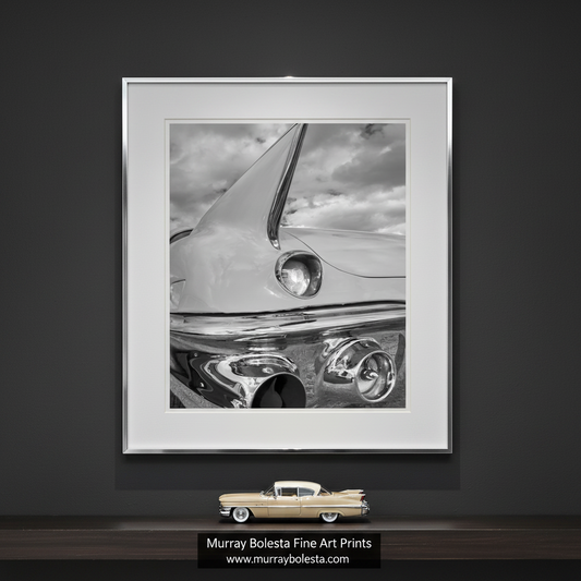 A close-up black and white photograph of the front end of a classic car, focusing on the chrome bumper and headlights. Black and White Cadillac Photo Art Print with Tail Fins by Murray Bolesta