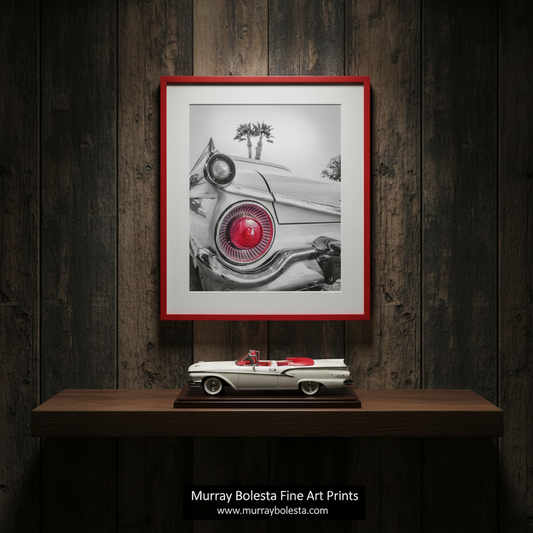 A black and white photograph of a classic car with a red tail light, featuring palm trees in the background. Ford Fairlane Photography Art Print as Automotive Wall Decor by Murray Bolesta