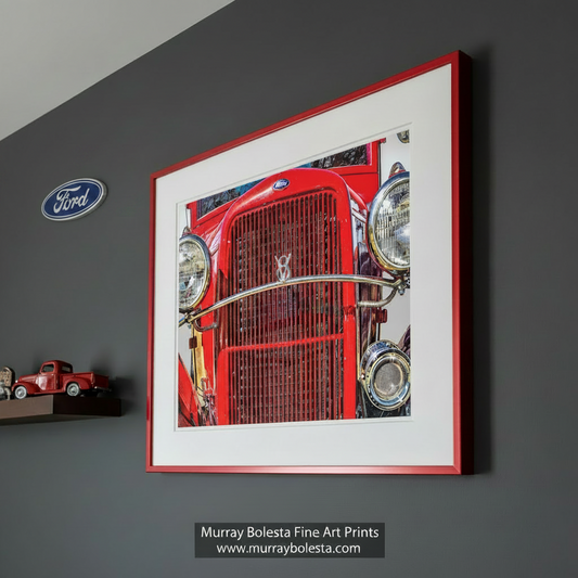 A close-up view of the front grille and headlights of a bright red vintage Ford car. Antique Ford Truck Picture as Vintage Automotive Wall Art by Murray Bolesta
