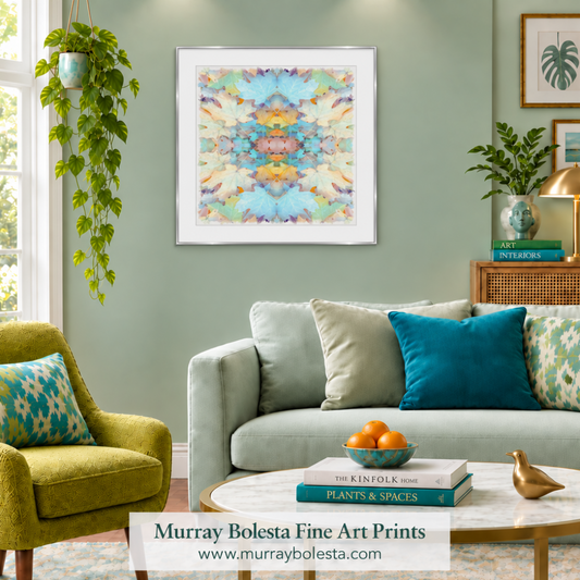 A framed abstract art print with a symmetrical kaleidoscope pattern in pastel shades of blue, yellow, green, and pink, displayed on a sage green wall in a styled living room setting. The print is presented on a white background with a watermark banner at the bottom. by Murray Bolesta.