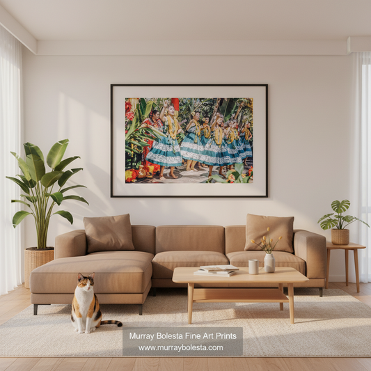 Mid-century tourist hula! A framed colorful art print depicting a festive Hawaiian folk dance scene hangs on a light beige wall above a modern tan sectional sofa in a bright, styled living room. A cat sits on the rug in the foreground, and a watermark for 'Murray Boleta Fine Art Prints' is visible at the bottom.