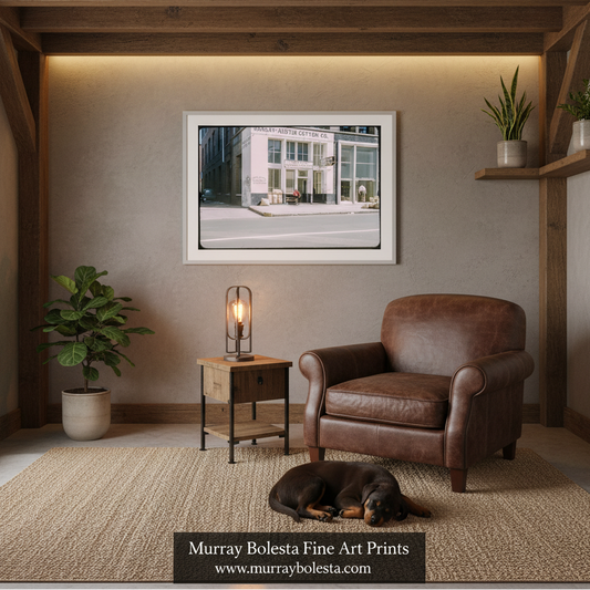 Memphis vintage cotton. A framed art print by Murray Boleta hangs on a textured gray wall in a styled room setting. The print depicts a white building with green trees.