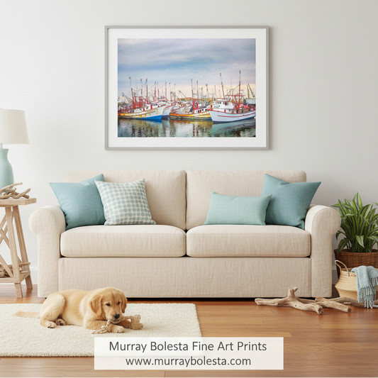 A framed art print of colorful fishing boats in a harbor hangs on a white wall above a beige sofa in a styled living room. A golden retriever lies on a white rug on the wooden floor below.