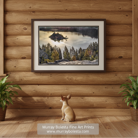 a serene lake surrounded by a forest of tall trees, with a small island visible in the center of the lake. The scene is captured during the day, with the sun's reflection visible on the water's surface. Tahoe Serene Wall Decor | Peaceful Emerald Bay Sunrise Art Print by Murray Bolesta!