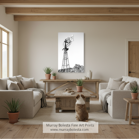 Tucson ranch windmill by Murray Bolesta! A black and white canvas print of a windmill landscape, mounted on a beige wall in a modern, neutral-toned living room with a dog sitting on the floor in front of it.