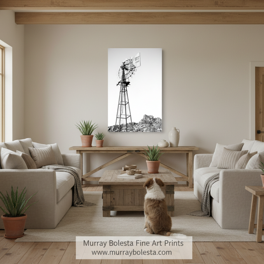 Tucson ranch windmill by Murray Bolesta! A black and white canvas print of a windmill landscape, mounted on a beige wall in a modern, neutral-toned living room with a dog sitting on the floor in front of it.