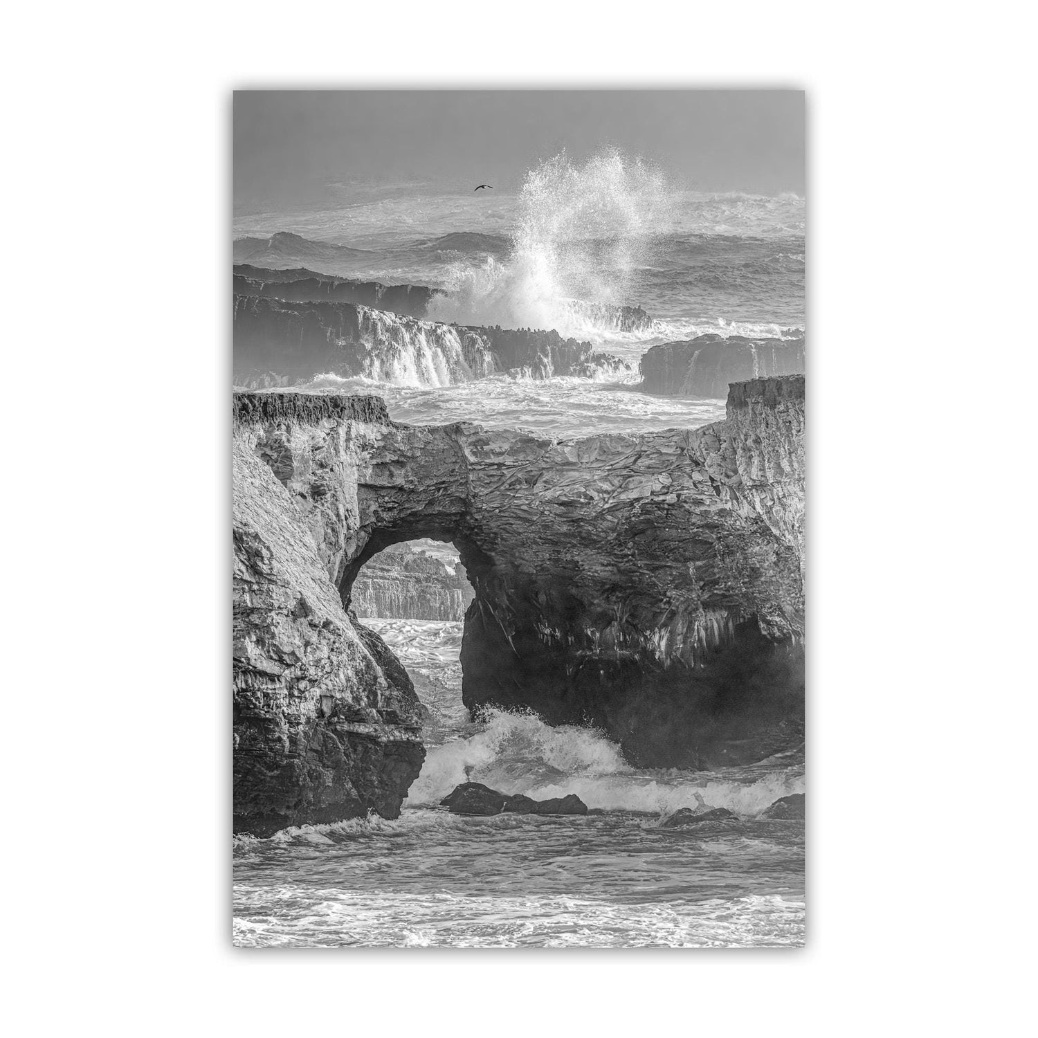 A dramatic black and white image of a rocky coastline with crashing waves, featuring a large archway or rock formation in the foreground. Mendocino Coast Painterly Seascape – Fine Art Print Point Arena