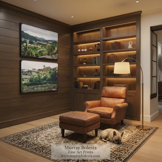A styled interior room with dark wood bookshelves and wall art, a brown leather armchair and matching ottoman, a patterned rug, and a small dog lying on the floor. Two framed landscape prints are mounted on the left wall. Vintage Road Trip art prints by Murray Bolesta.