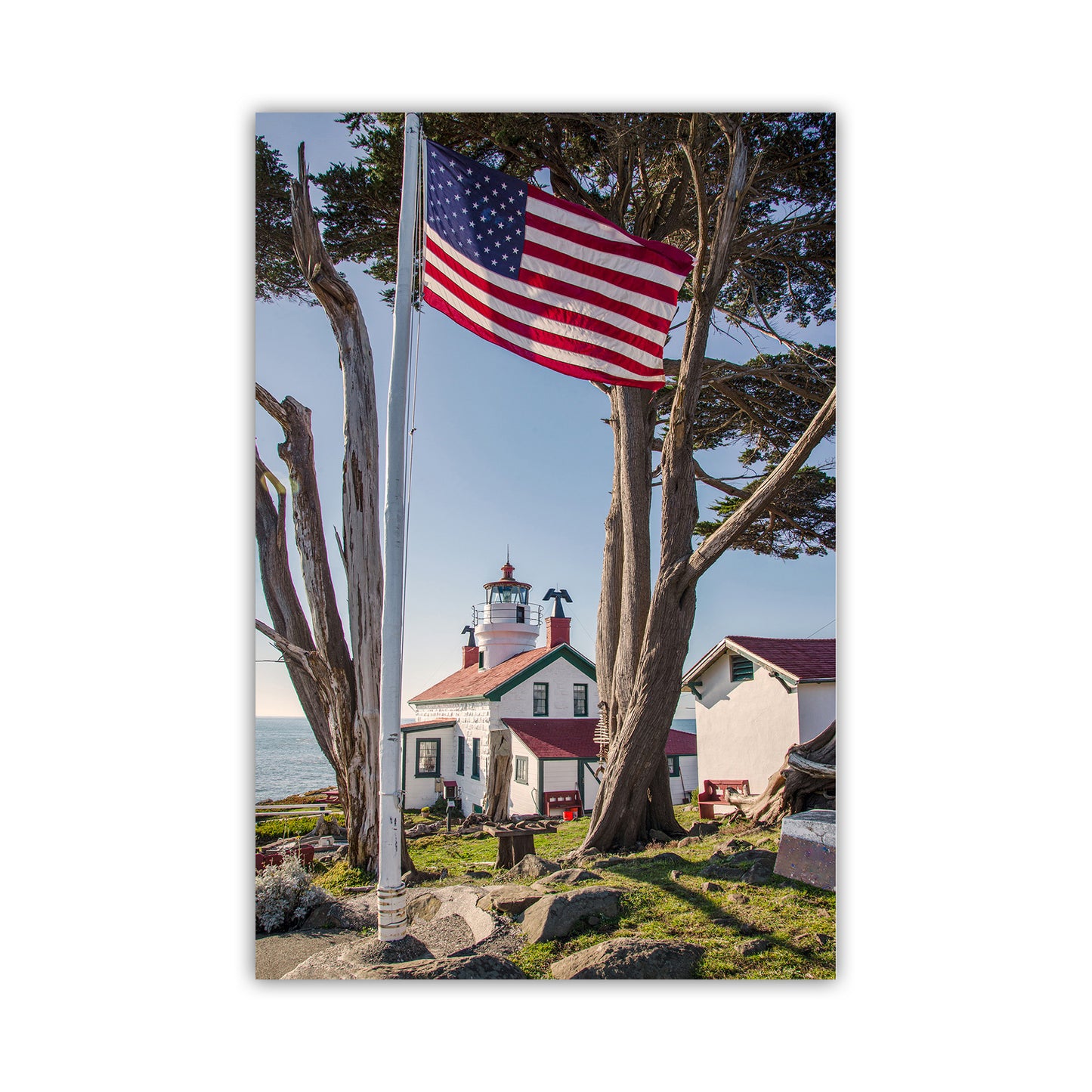 Lighthouse with American flag and trees in the foreground. Beautiful lighthouse art! For your walls, my cool lighthouse print from Crescent City, California. In the heart of Northern California's redwood coast, this is Del Norte County and the North Coast. This was one of the earliest lighthouses constructed on the USA West Coast, soon after California became a state. Original, unique signed art photograph by Murray Bolesta.