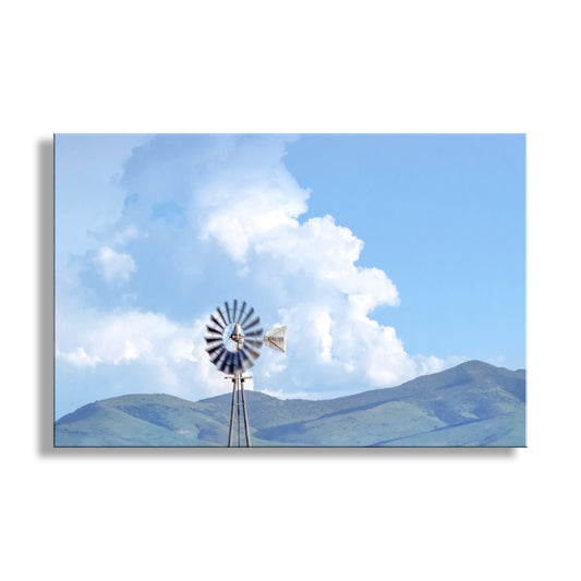 Windmill against a blue sky with white clouds. Farm Windmill Picture with Borderlands Arizona Landscape & Storm Clouds