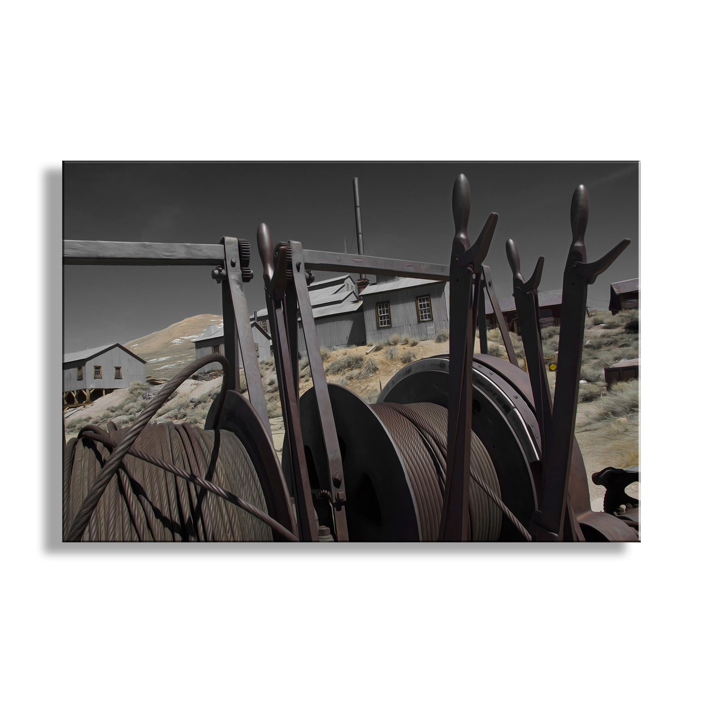 Vintage metal reels with a desert landscape and buildings in the background. My unique artwork of the time-worn ghost mining camp of Bodie! This place is a precious relic of western USA heritage in the high California desert, lovingly protected by vigilant state park staff. Original, unique signed art by Murray Bolesta.