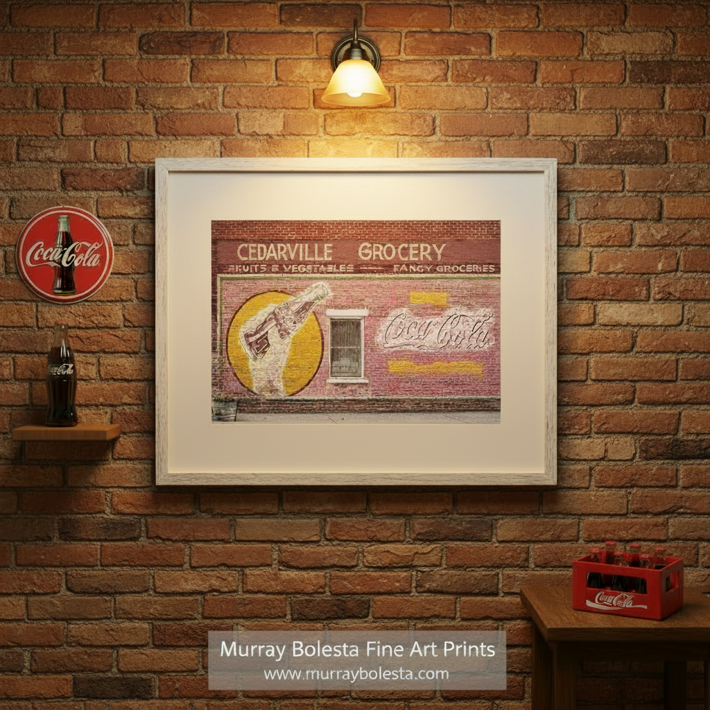 Framed artwork of a vintage Coca-Cola advertisement on a brick wall with 'Cedarville Grocery' text. Vintage Coca Cola Street Sign on Brick Wall in Cedarville California by Murray Bolesta