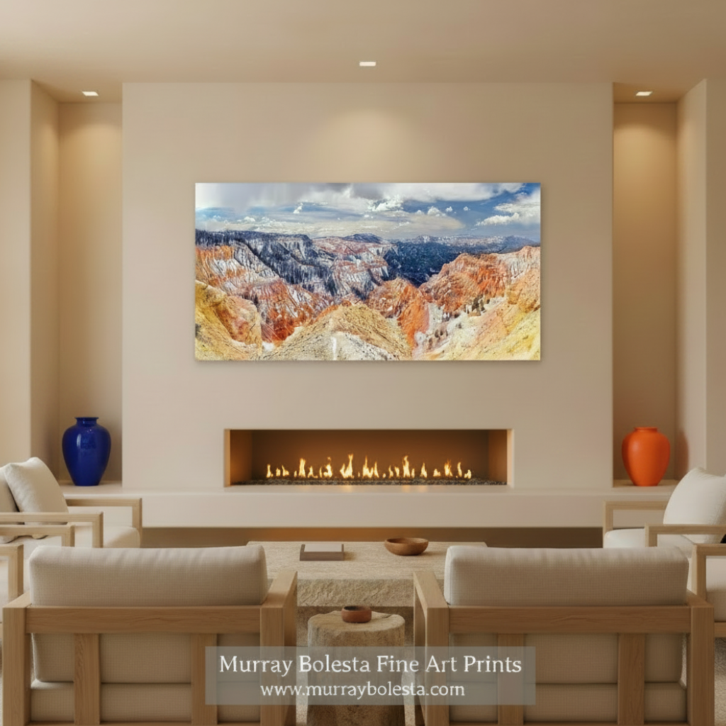 A panoramic view of a mountainous landscape with vibrant red and orange rock formations, snow-capped peaks, and a cloudy blue sky. Cedar Breaks Utah National Park Panorama Art Print by Murray Bolesta
