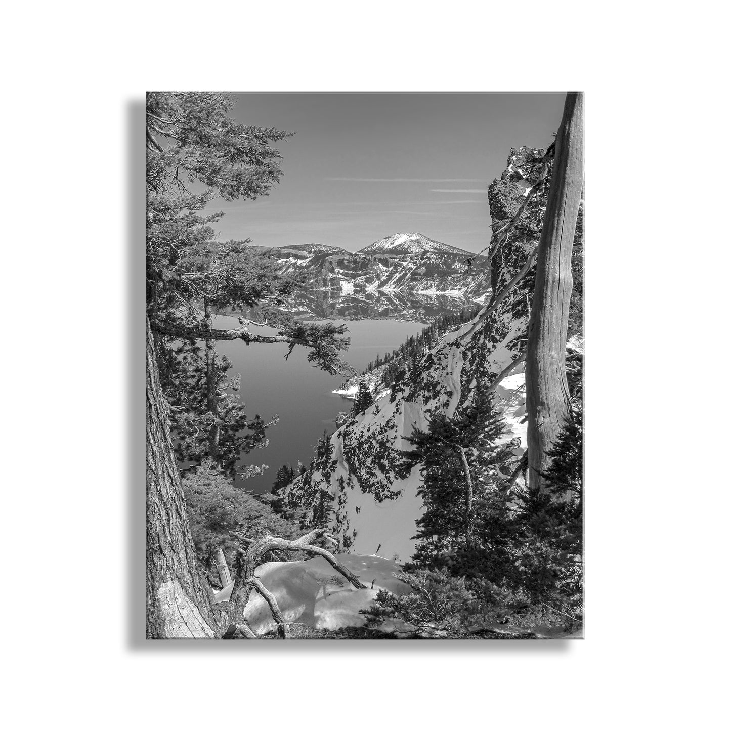 Black and white landscape of a lake surrounded by mountains and trees. My beautiful black & white picture of Crater Lake Oregon in all its wintertime splendor! This alpine lake is the result a colossal explosion in which Mount Mazama lost its head in a fit of pique. Since it happened only 7 or 8 thousand years ago, Native Americans actually witnessed the cataclysm which eventually provided a deep repository for a whole lot of very pure water!