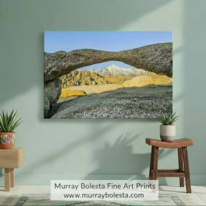 a large rock archway in a desert landscape, with mountains visible in the background under a clear blue sky. Alabama Hills Art Print | Mt Whitney California Landscape Photography by Murray Bolesta