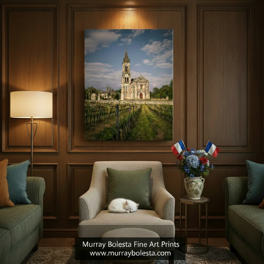 a large, ornate church with a tall steeple, surrounded by a vineyard with rows of grapevines. The sky is blue with some clouds, and the overall scene has a peaceful and picturesque quality. Bordeaux Vineyard Landscape Art | Romanesque Church Wine Country by Murray Bolesta