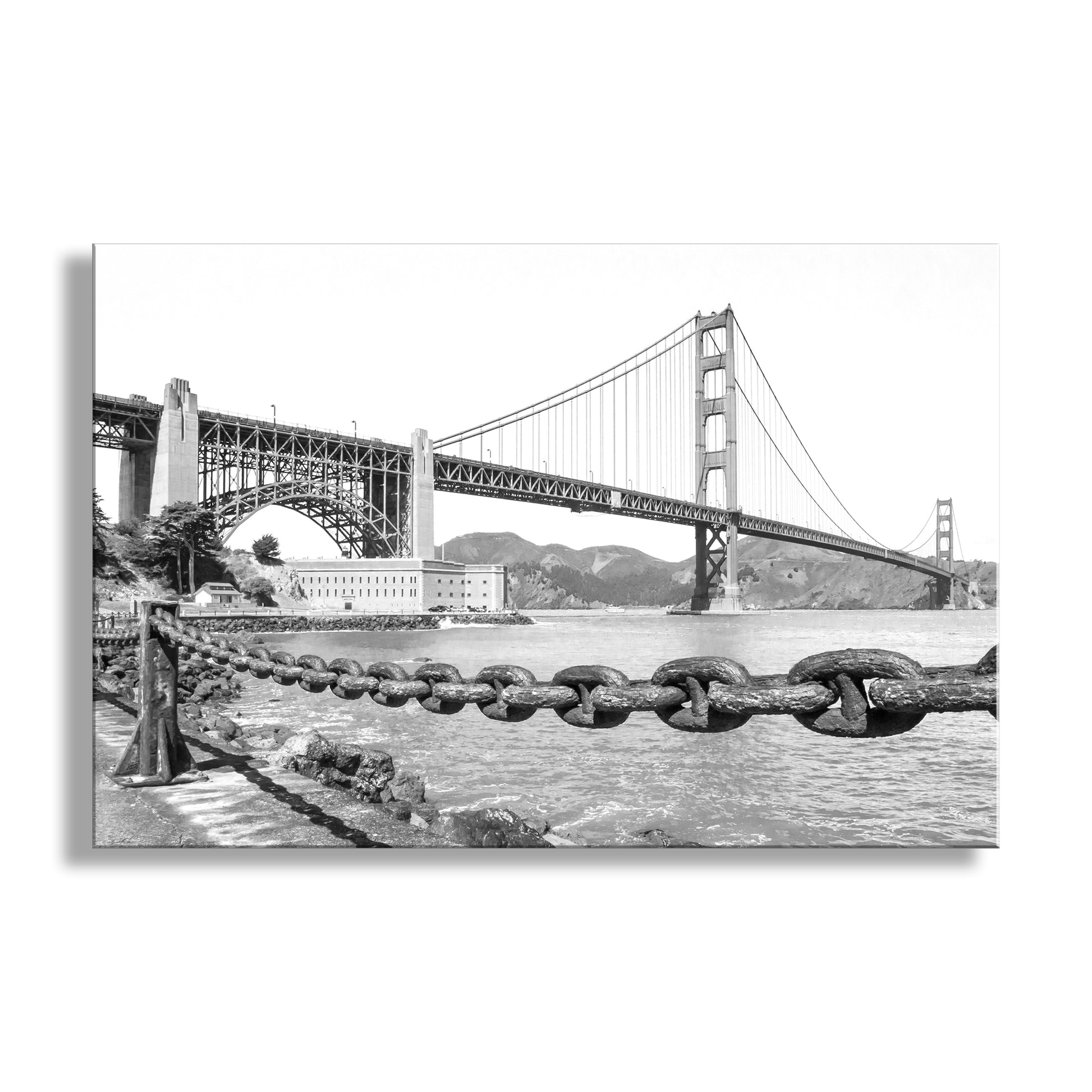 Black and white image of the Golden Gate Bridge with a large chain in the foreground. Beautiful black and white photo art! My terrific picture of historic Fort Point, San Francisco. The 19th-century Fort Point huddles under the mighty Golden Gate Bridge which was built to preserve the fort. This is scenic San Francisco at its best, and a reminder of a period when the U.S. military dominated much of the peninsula.