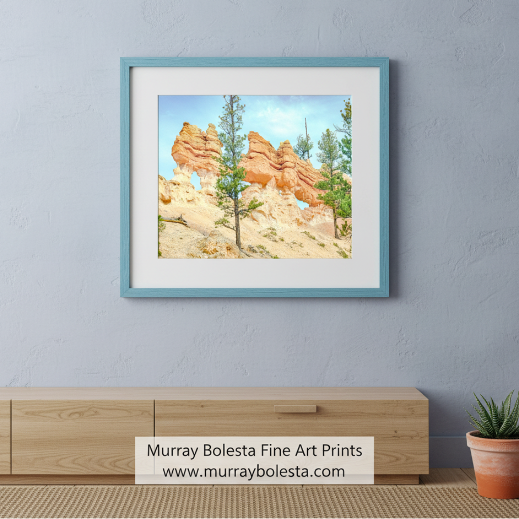 a rocky landscape with tall, orange-colored rock formations, including a large rock formation with a hole in the middle. The scene is surrounded by trees and shrubs, creating a natural and picturesque setting. Bryce Canyon Utah Desert Hoodoo Landscape Art Print by Murray Bolesta