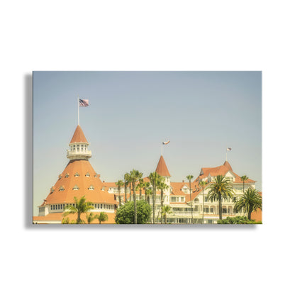 Hotel with a red roof and flag, surrounded by palm trees against a clear sky. This is fabulous Hotel Del Coronado, San Diego California, a vacation destination for generations of beach-goers, all the way back to the 19th century! The hotel was an important filming location for the classic movie comedy "Some Like it Hot." Your artwork is presented in a vintage style. Original, unique signed art by Murray Bolesta!