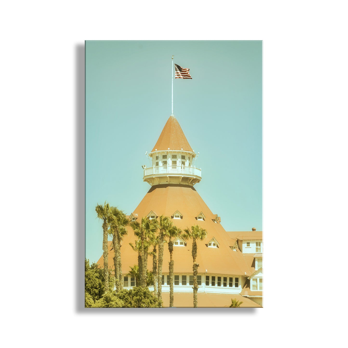 Building with a cone-shaped roof and American flag against a light blue sky. This is Hotel Del Coronado, San Diego California, a vacation destination for generations of beach-goers, all the way back to the 19th century! The hotel was an important filming location for the classic movie comedy "Some Like it Hot." This art is presented in a vintage style. Original, unique signed art by Murray Bolesta!