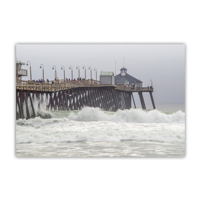 Pier with people on it surrounded by large waves on a cloudy day. Imperial Beach Pier Photo – Pacific Ocean Waves San Diego California