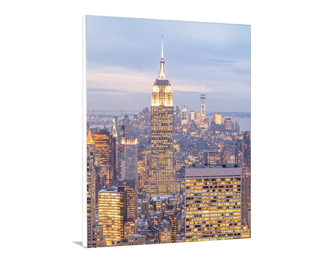 Cityscape with illuminated buildings, featuring the Empire State Building, on a clear sky. New York City Skyline Empire State Building at Dusk | Vertical Wall Art