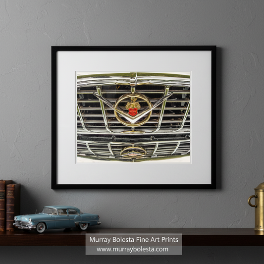 a close-up view of a car's front grille, featuring a prominent emblem with a red and gold design. Vintage Packard Abstract Wall Art | Car Decor Home & Garage by Murray Bolesta