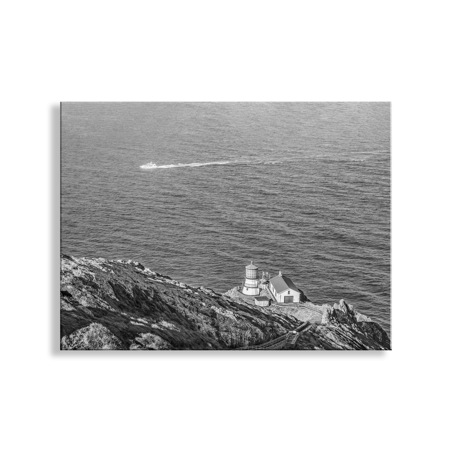 Lighthouse on a cliff overlooking the ocean with a boat in the distance. Point Reyes Lighthouse Picture in Black & White | California Coast Art