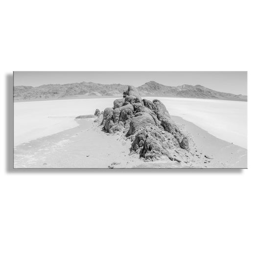 Black and white landscape of a rocky outcrop in a desert with distant mountains. The Racetrack. Black and White Wide Desert Panorama Wall Art with Death Valley National Park