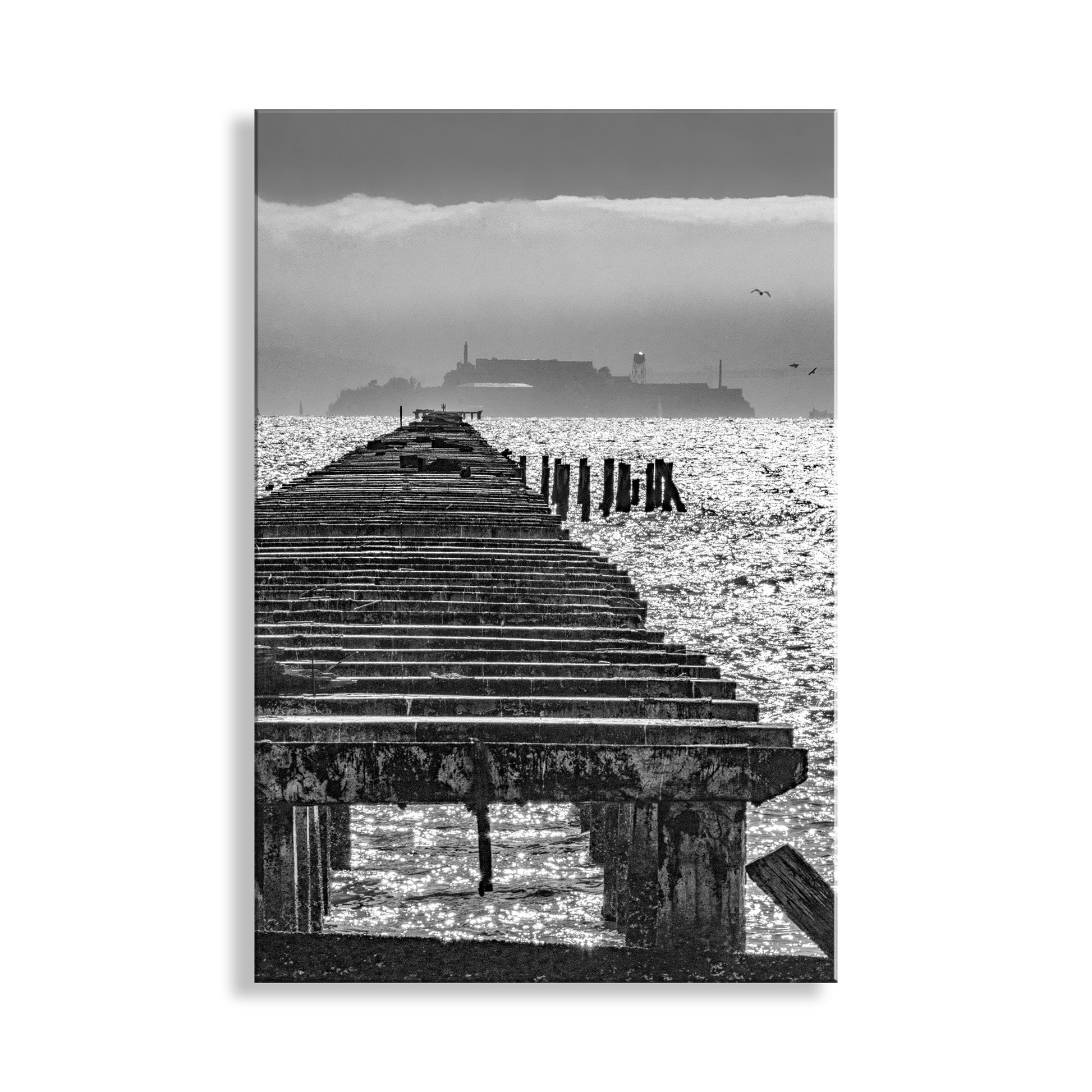 Black and white image of a wooden pier extending into water with a distant landmass. My beautiful Berkeley pier art print for your viewing pleasure! With Alcatraz Island in the distance, the foreground ruins are part of the pier that once extended an incredible 3 1/2 miles into the great San Francisco Bay. Original, unique signed art by Murray Bolesta.