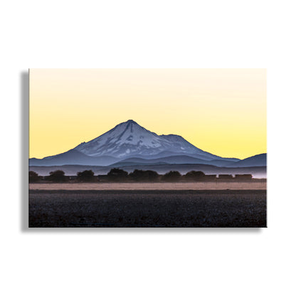 Mountain silhouette against a yellow sky with a white border. My splendid sunset photo with Mount Shasta and a train at dusk! This volcano rises majestically over fertile farmland of Northern California. Original, unique signed art by Murray Bolesta.
