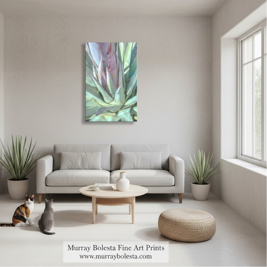 Agave pastel by Murray Bolesta! A framed abstract botanical art print hangs on a light beige wall above a modern light gray sofa in a bright, minimalist living room. The artwork features soft blended tones of green, teal, lavender, and pink.