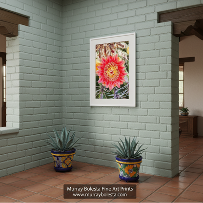 A vibrant red flower with yellow centers is the focal point of the image, surrounded by a blurred background of green leaves and stems. Barrel Cactus & Wildflower | Arizona Desert Botanical Art Print by Murray Bolesta