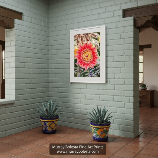 A vibrant red flower with yellow centers is the focal point of the image, surrounded by a blurred background of green leaves and stems. Barrel Cactus & Wildflower | Arizona Desert Botanical Art Print by Murray Bolesta