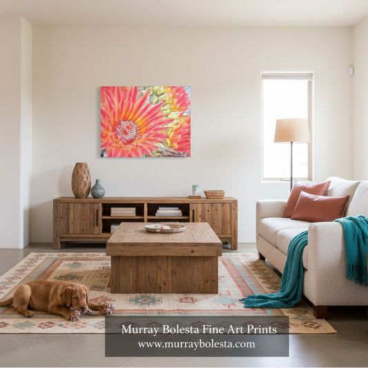 A bright living room with a large colorful floral wall art print above a wooden media console. A beige sofa with pink pillows and a teal throw sits to the right, and a brown dog rests on a patterned rug on the left.