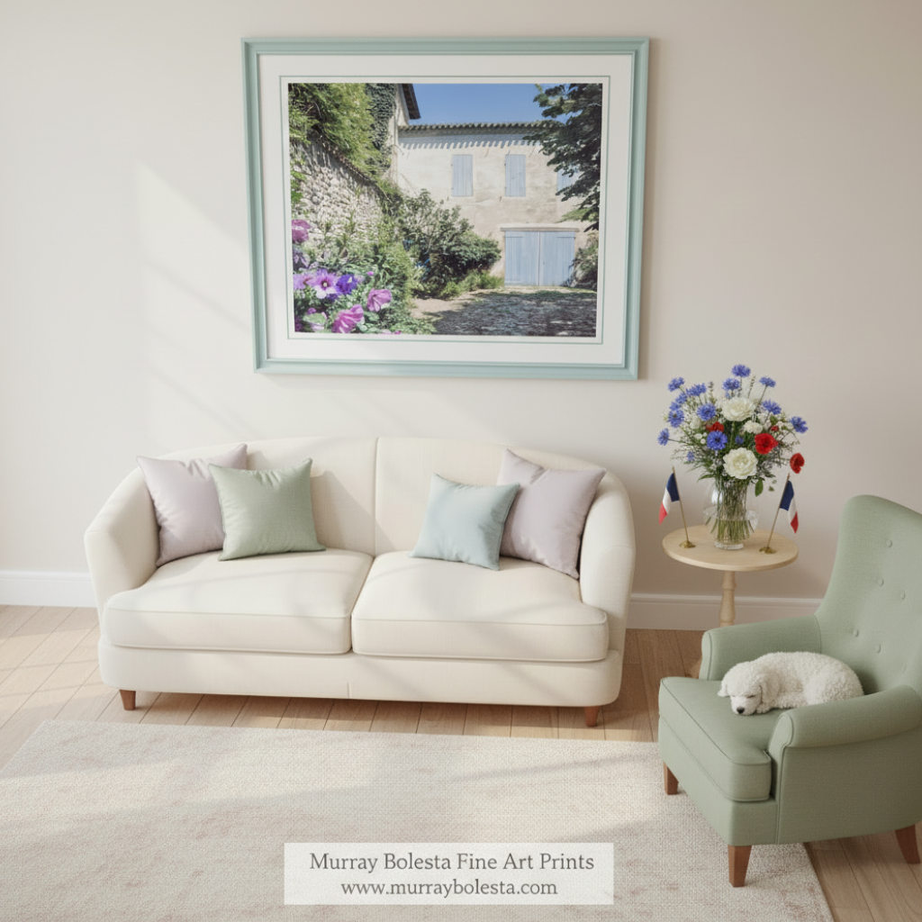 a charming stone building with blue shutters, surrounded by lush greenery and vibrant purple flowers. Quaint France Stone Cottage Print | French Village Wall Art by Murray Bolesta!