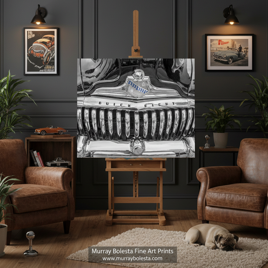 Buick Car art! A framed black-and-white art print depicting a vintage car grille and emblem, displayed on a wooden easel in a styled living room with brown leather armchairs, potted plants, wall sconces, and a small dog on a rug. The text 'Murray Bolesta Fine Art Prints' appears at the bottom.