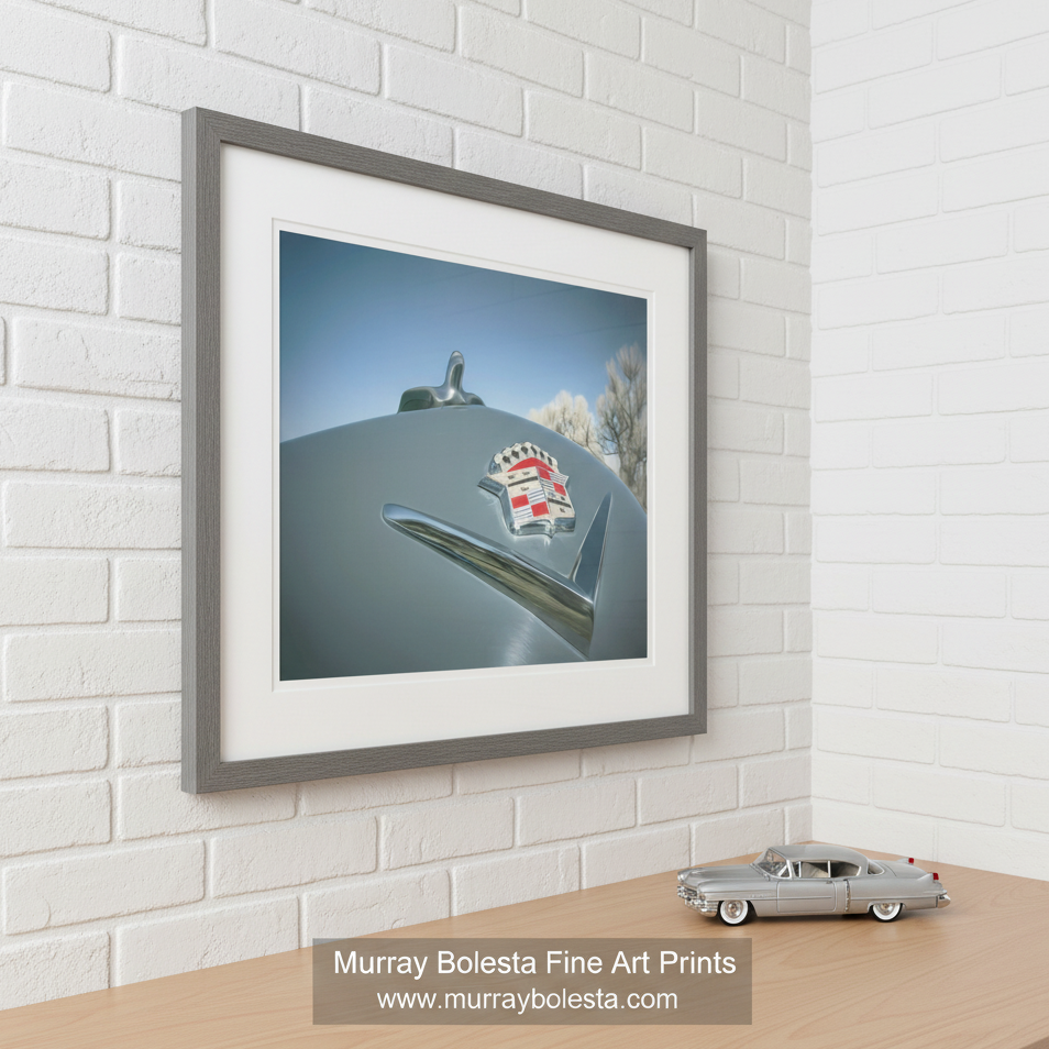 a vintage car with a chrome emblem on the hood, set against a backdrop of a blue sky with fluffy white clouds. Cadillac Car Art as Automotive Wall Decor by Murray Bolesta