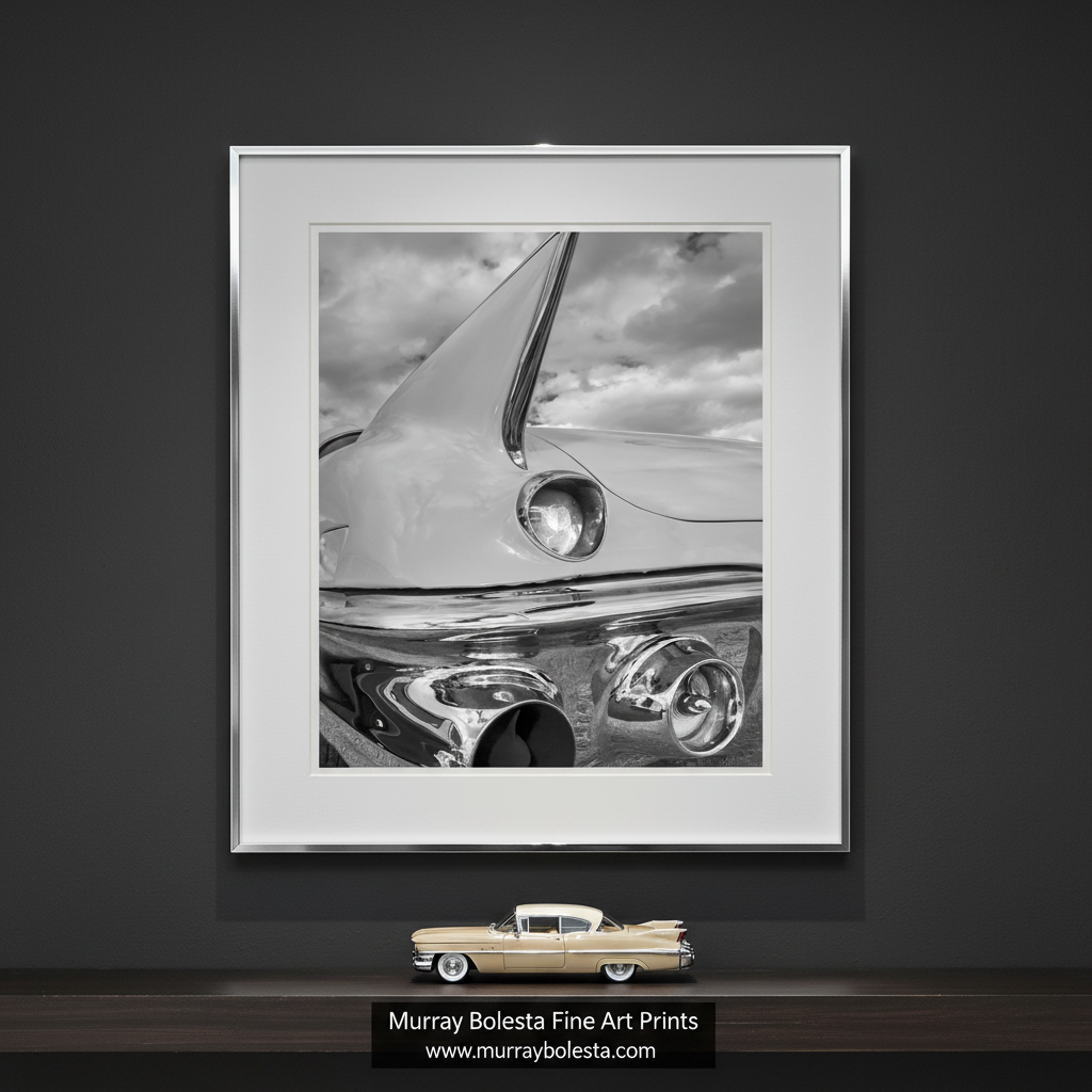 A close-up black and white photograph of the front end of a classic car, focusing on the chrome bumper and headlights. Black and White Cadillac Photo Art Print with Tail Fins by Murray Bolesta